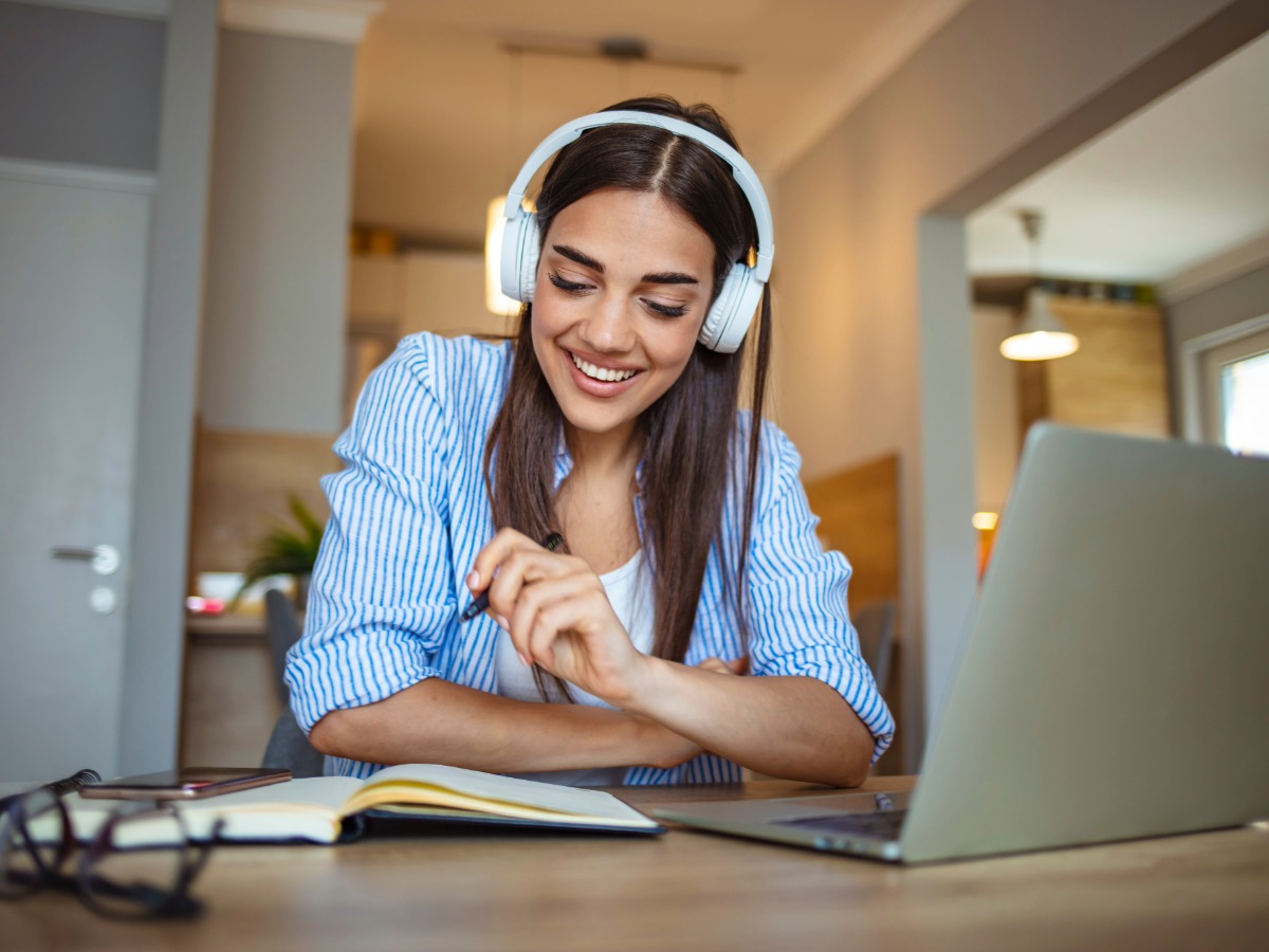 In Walton, NY, a woman with a headset smiles at her laptop, showcasing Delhi Telephone Co as a leading Fiber Internet Provider.